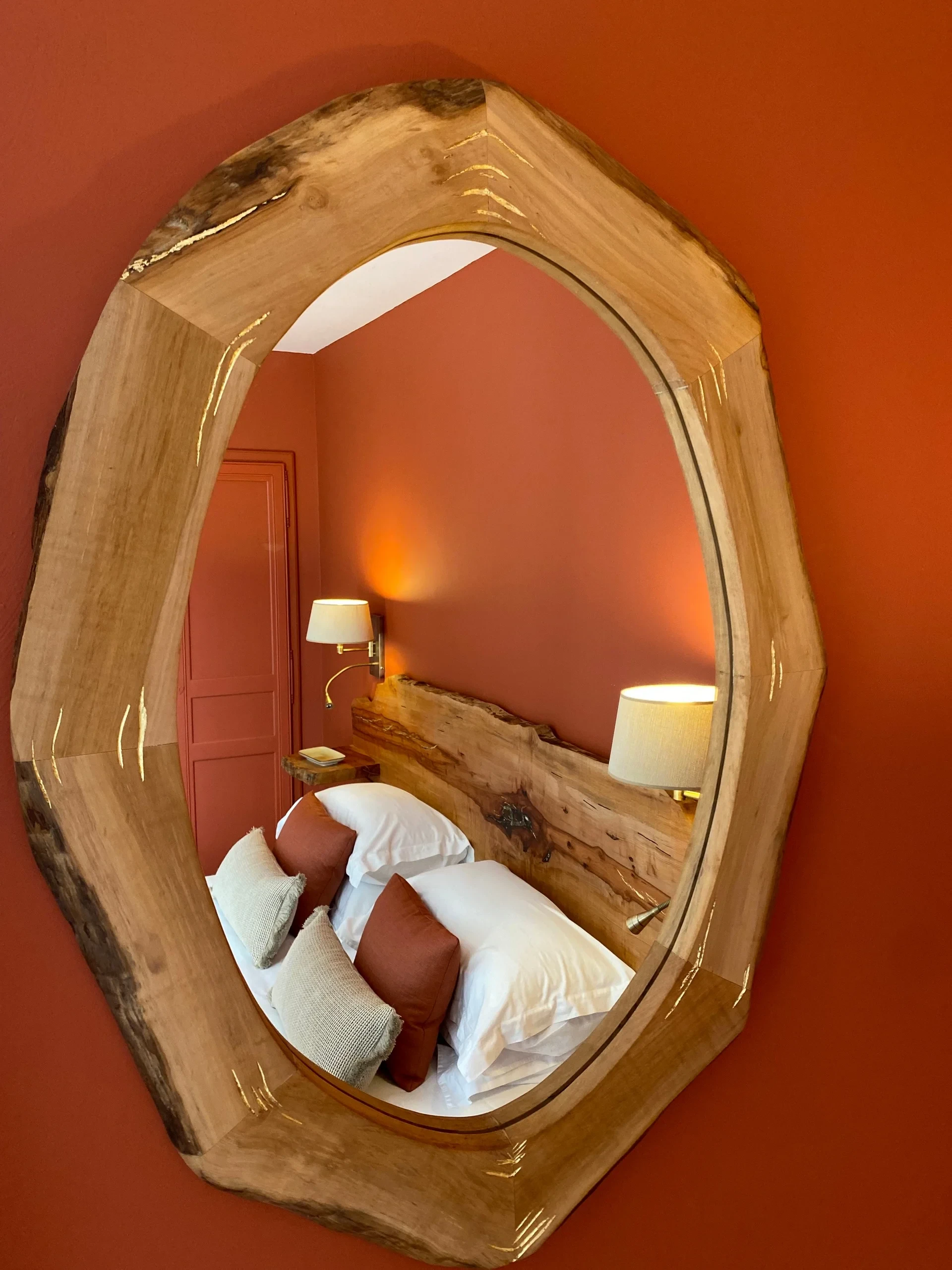 Miroir ovale en bois reflétant un lit cosy