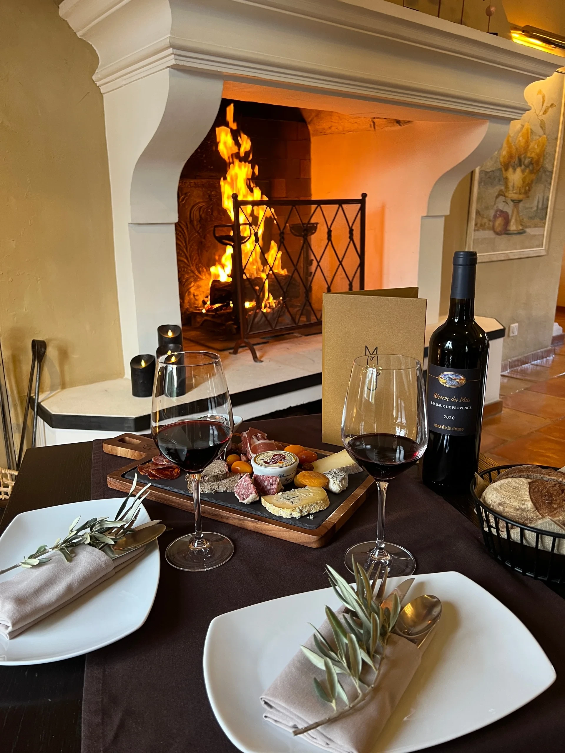 Table romantique avec vin et charcuterie devant feu de cheminée