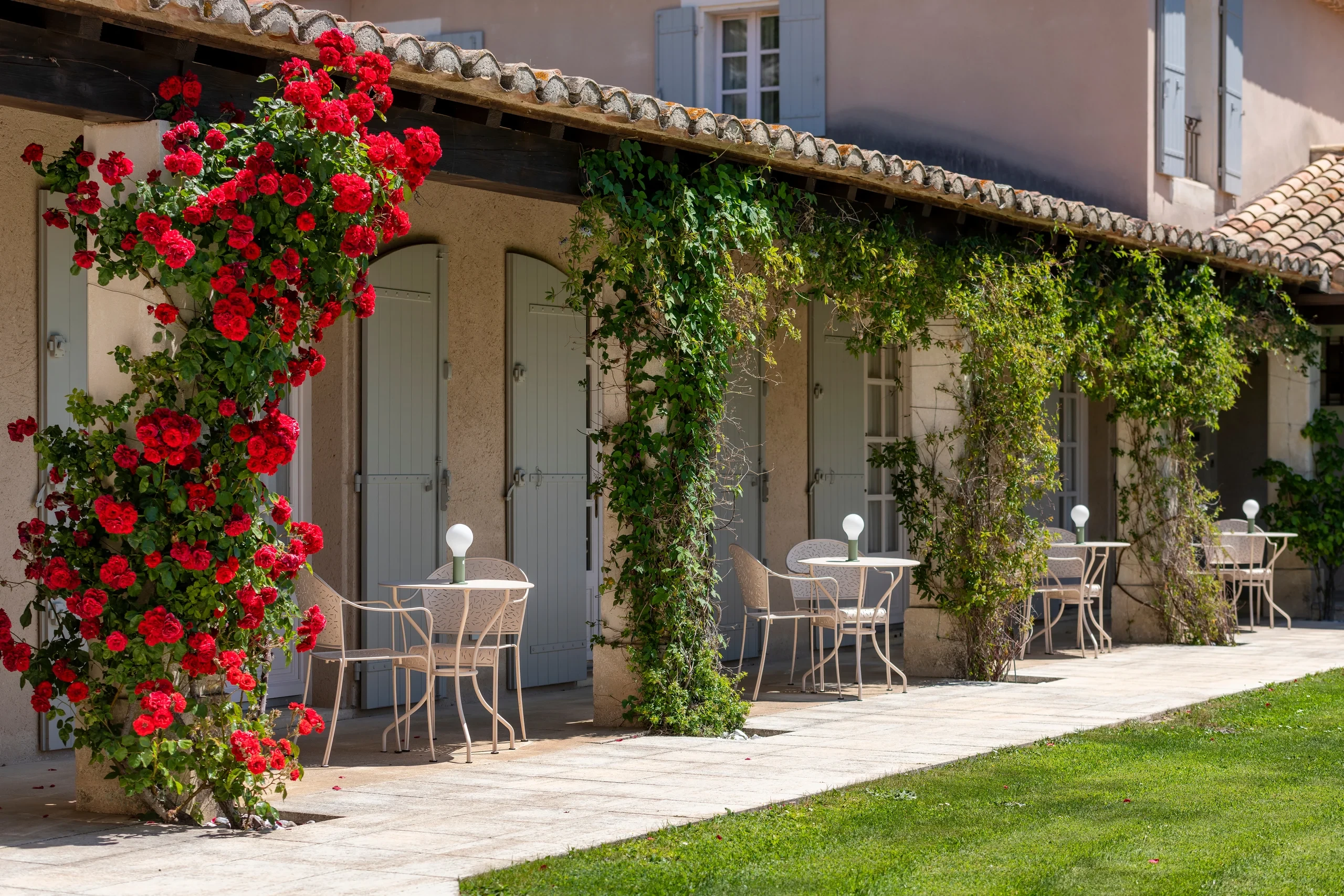 Terrasse de maison avec rosiers et tables en fer